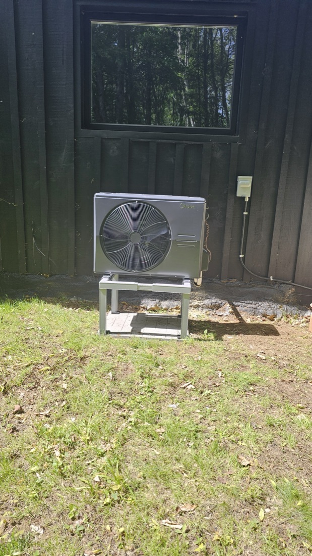 Heat pump installed beside a dark-sided cottage